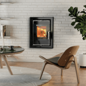 The Athens black glass cassette stove embodies a sleek, modern design and a large viewing glass. The stove is pictured here in black with chrome trim and handle set into a white brick feature wall