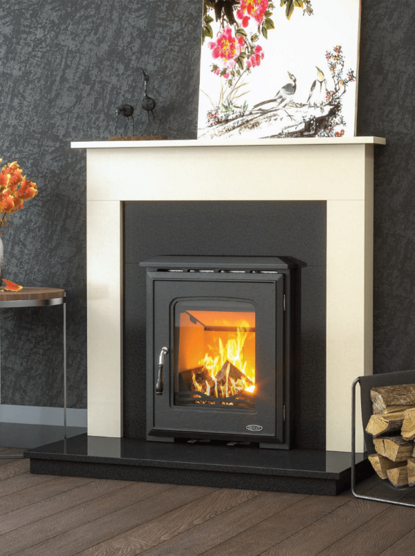 The Castlecove is a fully cast-iron stove pictured here in black with a chrome handle and large viewing window, with blazing fire within. The Castlecove is pictured set into a black granite insert and limestone surround with a black granite hearth beneath.
