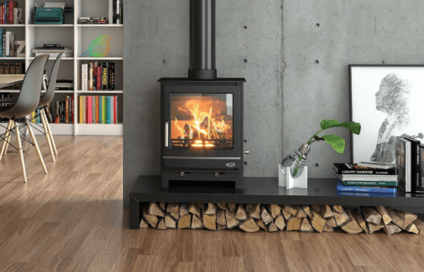 The free standing Hampshire stove boasts a sleek and clean design. Pictured here in black with matching pipe work and chrome handle, this stove comes in a simple rectangular shape with a large viewing window. Set upon the optional extra log store stacked with kindling and against a concrete finish feature wall
