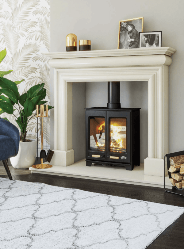 The new Hampton is a Steel body stove with classic cast iron double doors. Pictured here in black with matching black pipe work and a warm fire blazing behind the viewing glass of each of the double doors. The fire is set within an elegant white surround and hearth