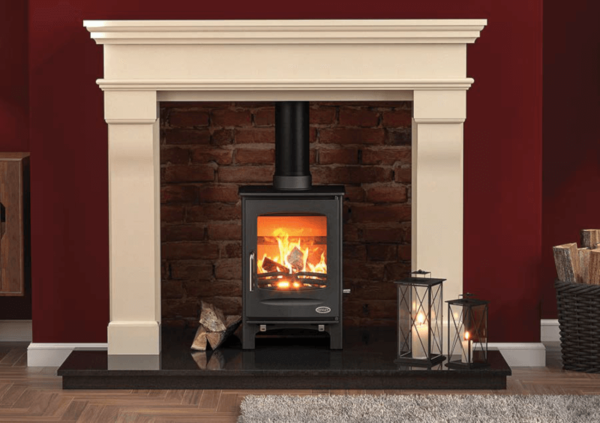 Pictured here is a classic black Sherwood free standing 5kW stove with matching black pipework. The stove is an elegant small rectangular shape, it is set upon a black granite hearth, within a red brick chamber and a stunning white stone fireplace surround