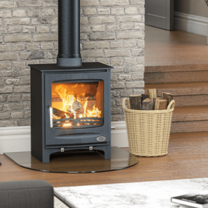 Elegant Sherwood free standing stove, pictured here in black with chrome handle and large viewing window with blazing fire inside. The stove is set upon a circular hearth against a grey brick feature wall and has matching black pipework