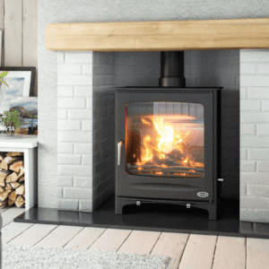 Black 25kW Freestanding Henley Boiler Stove, positioned in grey painted brick chamber with black granite hearth and timber mantle