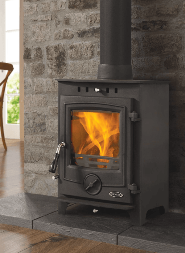 The Thames multi fuel stove is manufactured from steel with a cast iron door. It is ideal if you have limited space on your hearth. Pictured here in black with blazing fire in the viewing window, set against a stone clad feature wall